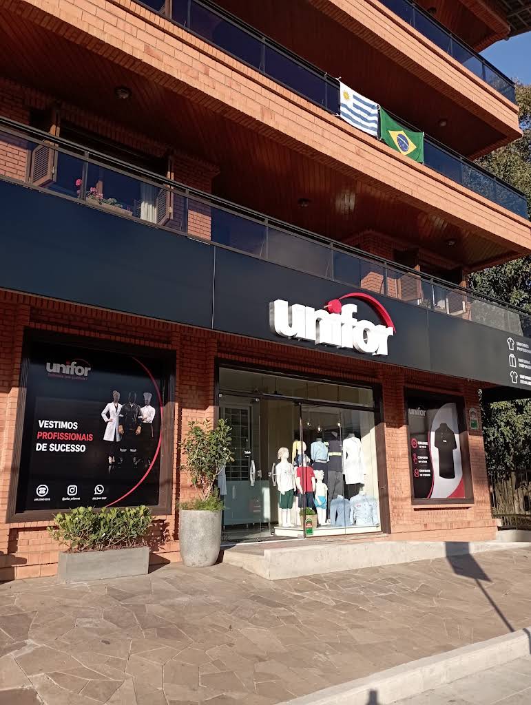 Fachada da UNIFOR Uniformes em Concórdia, com a marca na entrada e vitrine de produtos.